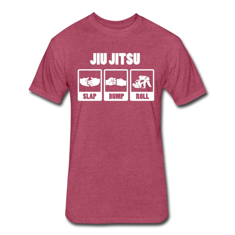 May include: A red heather t-shirt with white text that reads "JIU JITSU" and three white boxes with illustrations of hands slapping, bumping, and rolling. The text below the boxes reads "SLAP BUMP ROLL".