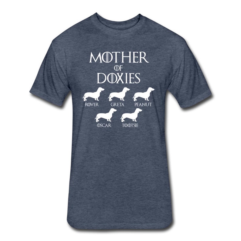 May include: A navy blue t-shirt with the text "Mother of Doxies" in white. Below the text are five white silhouettes of Dachshunds with the names "Rover", "Greta", "Peanut", "Oscar", and "Tootsie" underneath each silhouette.