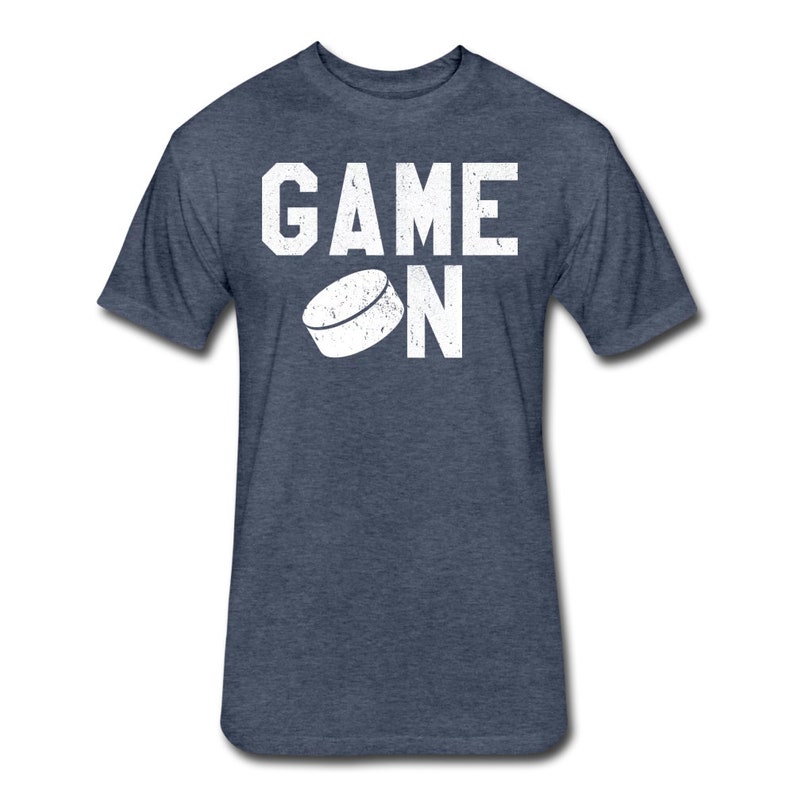 May include: A navy blue t-shirt with a white graphic of a hockey puck and the text "GAME ON".