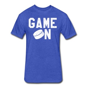 May include: A royal blue t-shirt with a white distressed graphic of a hockey puck and the text "GAME ON".