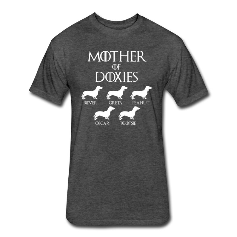 May include: A dark heather grey t-shirt with a white graphic of a dachshund silhouette and the text "Mother of Doxies". The graphic includes the names of five dachshunds: Rover, Greta, Peanut, Oscar, and Tootsie.