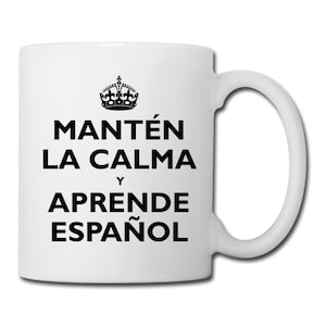 May include: White ceramic mug with a black crown and the text "Mantén la calma y aprende español" which translates to "Keep calm and learn Spanish".