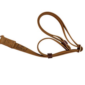 Op de afbeelding: Een bruine stoffen riem met een metalen draaibare musketonhaak aan het ene uiteinde en twee donkerbruine leren lussen langs de band. De stof is bedrukt met de tekst OTK-2 en het nummer 81 bij de metalen hardware.