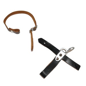 May include: Two leather straps, one brown and one black. The brown strap has a metal buckle and a snap closure. The black strap has a metal clip and a loop. Both straps are used for attaching items to a belt or backpack.