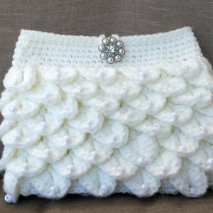 May include: White crocheted clutch purse with a pearl-like embellishment and a decorative rhinestone button.