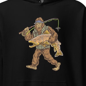 May include: Black hooded sweatshirt with a graphic of a Bigfoot holding a large trout. The Bigfoot is wearing a hat and holding a fishing rod.