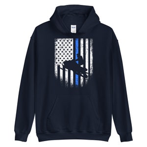 May include: A navy blue hooded sweatshirt with a distressed American flag design featuring a thin blue line and a silhouette of a person riding a snowmobile.