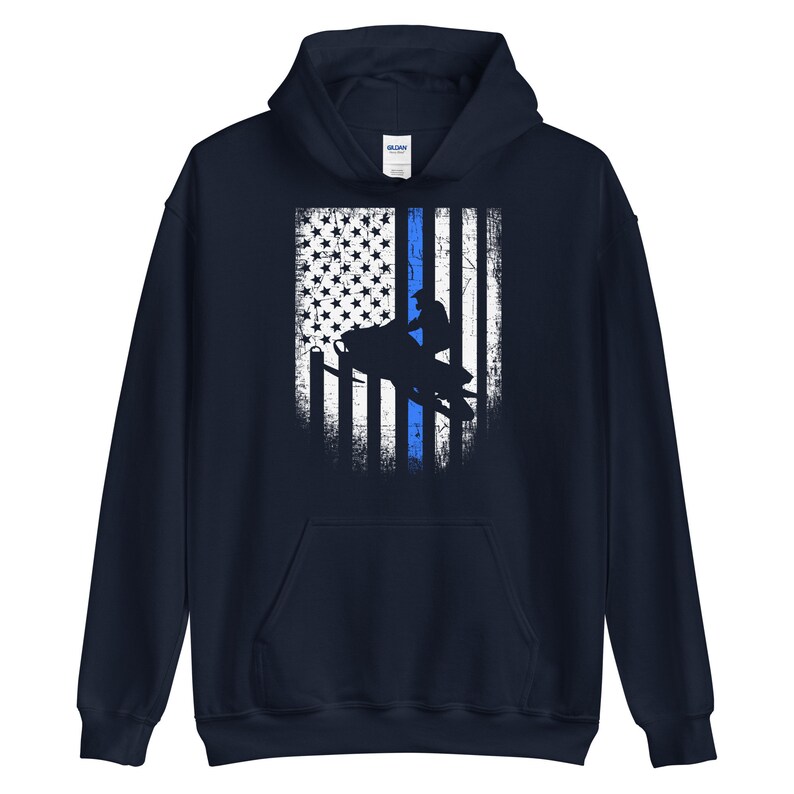 May include: A navy blue hooded sweatshirt with a distressed American flag design featuring a thin blue line and a silhouette of a person riding a snowmobile.