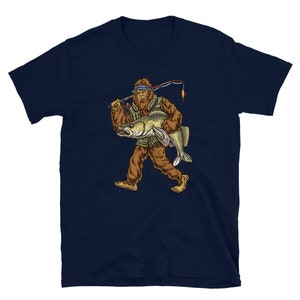 Op de afbeelding: Een marineblauw t-shirt met een afbeelding van Bigfoot die een vis en een hengel vasthoudt. Bigfoot draagt een vissersvest en een hoed.