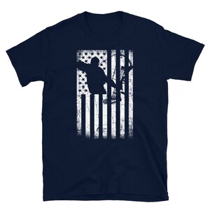 May include: Navy blue t-shirt featuring a distressed white graphic of an archer aiming a bow and arrow, set against a stylized American flag design. The design includes stars and stripes, creating a patriotic theme.