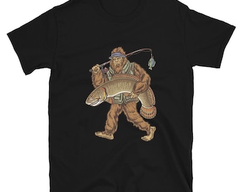 May include: Black t-shirt featuring a cartoon illustration of Bigfoot carrying a large fish. Bigfoot is wearing a fishing vest and hat, with a fishing rod over his shoulder. The fish has a detailed scale pattern.