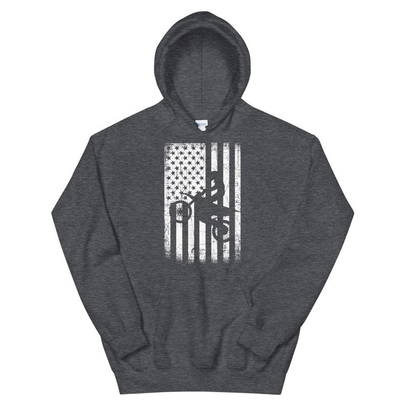May include: A dark grey hooded sweatshirt with a white distressed American flag design featuring a silhouette of a person riding a dirt bike.