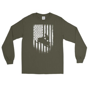 K&ouml;nnte beinhalten: Ein gr&uuml;nes Langarmshirt mit einem wei&szlig;en, abgenutzten amerikanischen Flaggen-Design, das die Silhouette einer Person auf einem Schneemobil zeigt.