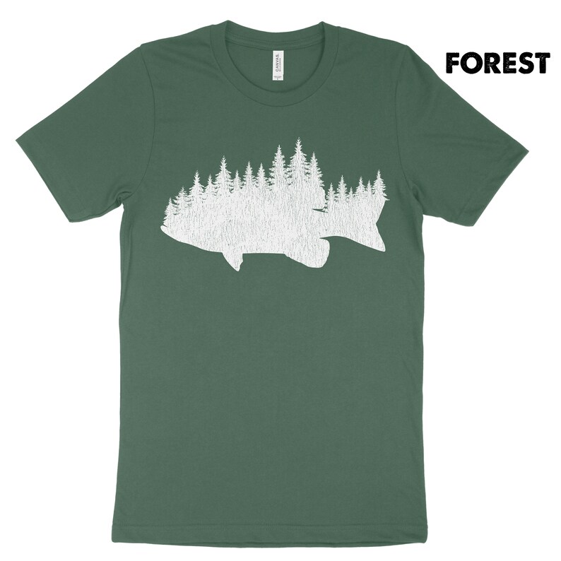 May include: Green t-shirt with a white graphic of a fish silhouette filled with a forest design. The word "FOREST" is printed in bold, black letters in the upper right corner. The shirt is made of a soft material.