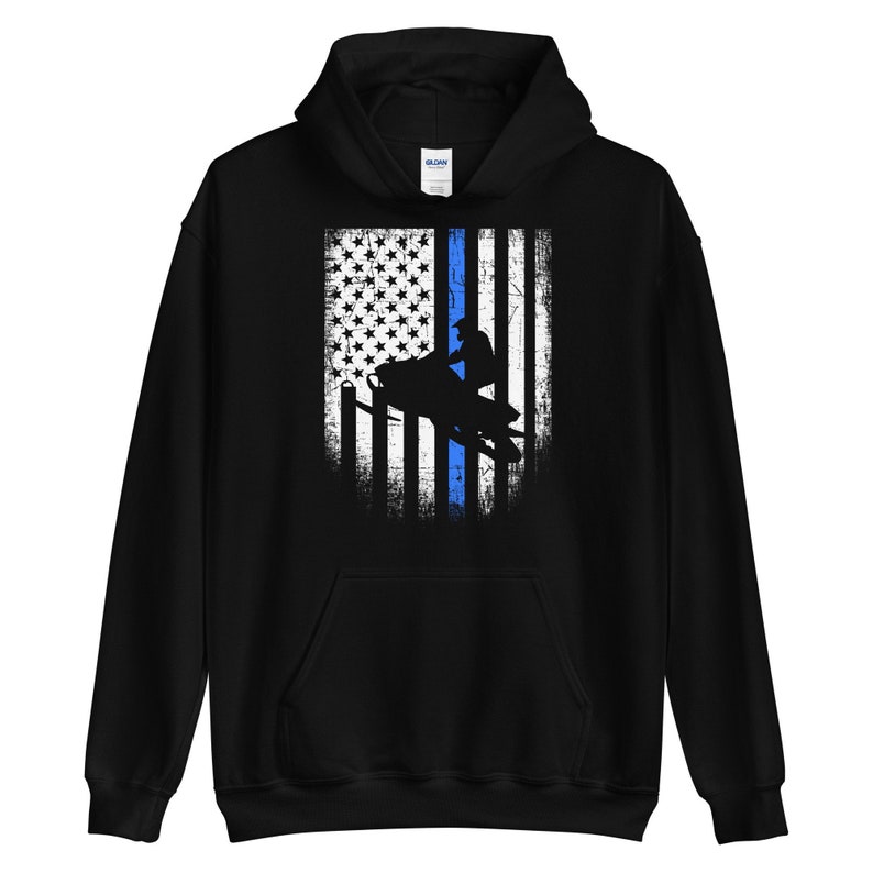May include: Black hooded sweatshirt with a distressed American flag design featuring a blue line down the center and a silhouette of a person riding a snowmobile.
