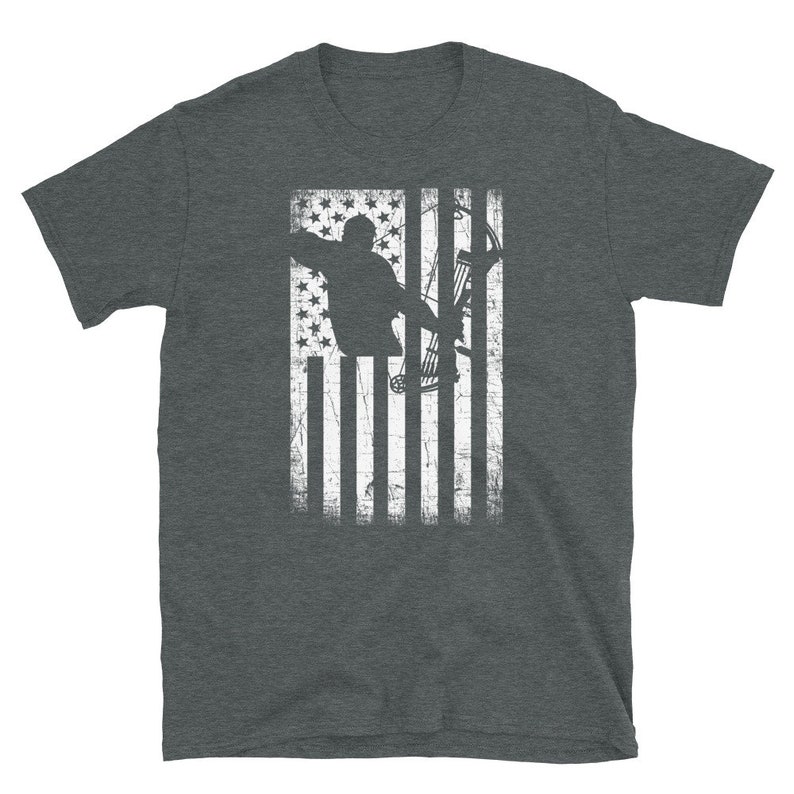 May include: Dark gray t-shirt featuring a distressed American flag design. The flag graphic includes a silhouette of a person aiming a bow and arrow. The design is in white, creating a patriotic and sporty look.
