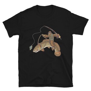 May include: Black t-shirt featuring a humorous illustration of a fisherman riding a large fish, holding a fishing rod. The fisherman is wearing a hat and vest. A smaller fish is on the hook. The design is in shades of brown, tan, and green.