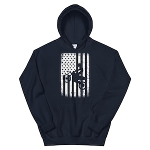 May include: A navy blue hoodie with a white distressed American flag design featuring a silhouette of a person riding a dirt bike.