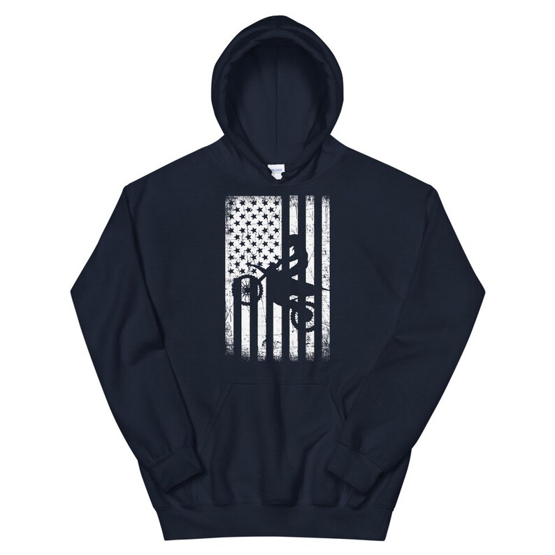 May include: A navy blue hoodie with a white distressed American flag design featuring a silhouette of a person riding a dirt bike.