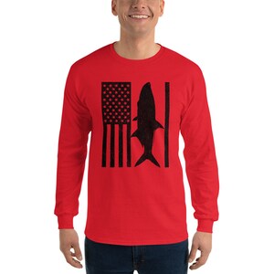 Pu&ograve; includere: Maglietta a maniche lunghe rossa con una silhouette nera di un pesce e una bandiera americana.