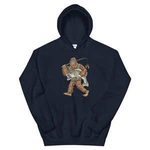 May include: A navy blue hooded sweatshirt with a graphic of a Bigfoot holding a fish. The Bigfoot is wearing a hat and holding a fishing rod.