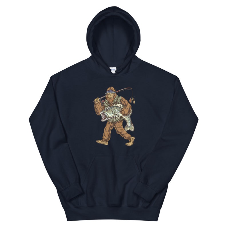 May include: A navy blue hooded sweatshirt with a graphic of a Bigfoot holding a fish. The Bigfoot is wearing a hat and holding a fishing rod.