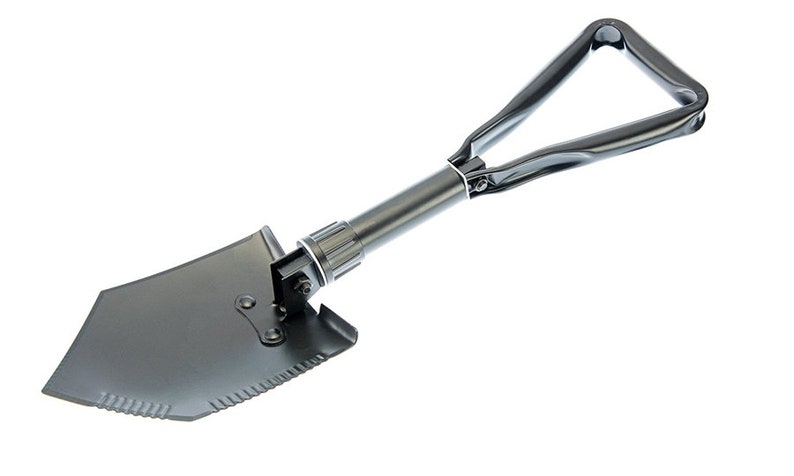 May include: A black folding shovel with a triangular handle. The shovel has a serrated edge and a pointed tip.