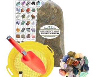 May include: A beginner's luck gemstone paydirt kit with a yellow sifting pan, a red shovel, a small bottle of liquid, and a bag of dirt containing various gemstones. The kit also includes a gemstone identification chart.