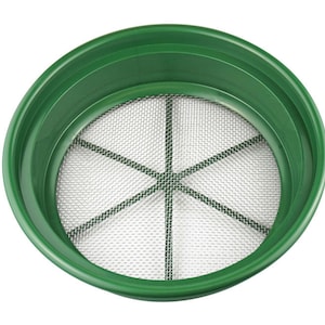 May include: A green plastic panning dish with a metal mesh screen. The screen has a circular shape and is divided into sections by metal bars.