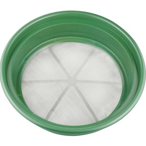 May include: A green plastic sifter with a white mesh screen. The screen has a starburst pattern of six spokes.