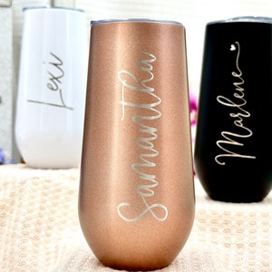 May include: Three stemless tumblers with lids, featuring a metallic rose gold finish with the name Samantha, a matte white finish with the name Lexi, and a matte black finish with the name Marlene, all engraved in a cursive script font.