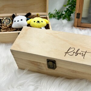 May include: A wooden box with a hinged lid and a brass latch. The box is engraved with the name "Robert".