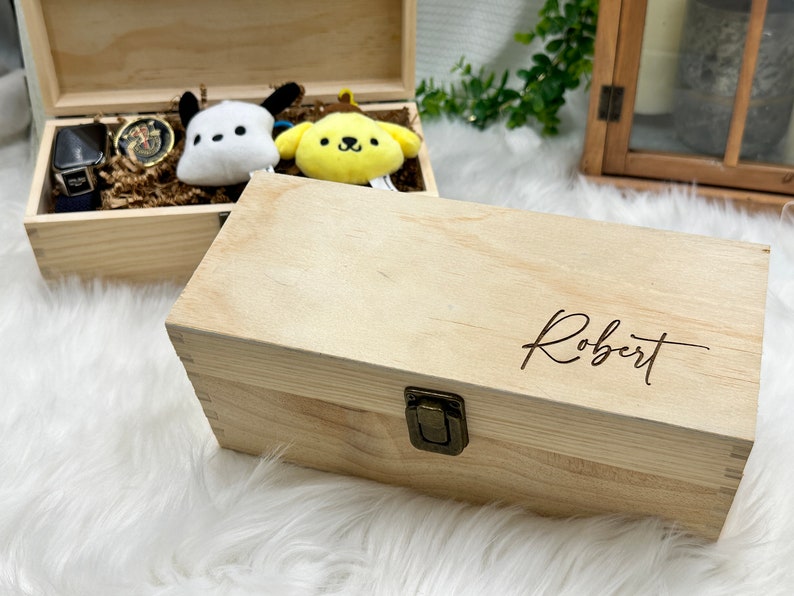 May include: A wooden box with a hinged lid and a brass latch. The box is engraved with the name "Robert".