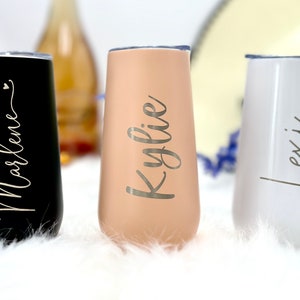 May include: Three stemless tumblers with clear lids, featuring a matte black finish with the name Marlene, a matte beige finish with the name Kylie, and a glossy white finish with the name Lexi, all written in a cursive script font.