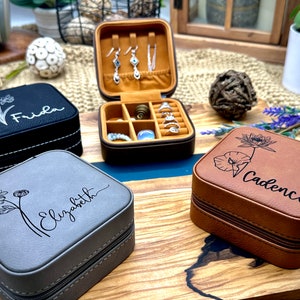 Puede incluir: Tres cajas de joyer&iacute;a diferentes con dise&ntilde;os florales y nombres personalizados. Las cajas est&aacute;n hechas de imitaci&oacute;n de cuero y tienen un cierre de cremallera. Los nombres en las cajas son Frida, Elizabeth y Cadence.