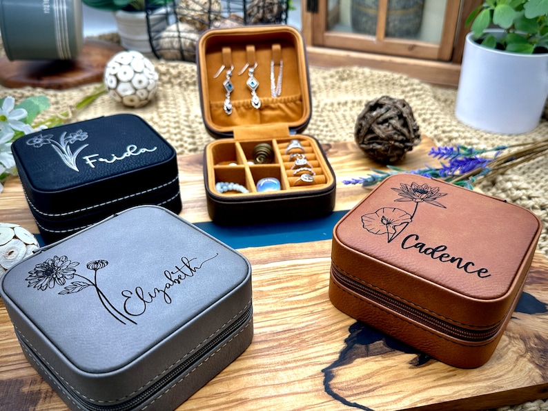 Puede incluir: Tres cajas de joyer&iacute;a diferentes con dise&ntilde;os florales y nombres personalizados. Las cajas est&aacute;n hechas de imitaci&oacute;n de cuero y tienen un cierre de cremallera. Los nombres en las cajas son Frida, Elizabeth y Cadence.