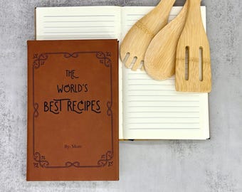 Może przedstawiać: Brązowa książka z przepisami z napisem "The World's Best Recipes" i ozdobną obwódką. Książka jest otwarta obok drewnianych przyborów kuchennych, w tym widelca i łyżki szczelinowej. Tekst "By Mom" znajduje się pod tytułem.