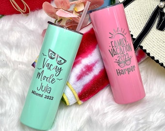 May include: Two stainless steel tumblers with personalised text. The green tumbler says "Vacay Mode Julia Miami 2022" with sunglasses and palm trees. The pink tumbler says "Family Vacation 2022 Harper" with a sun and sunglasses.