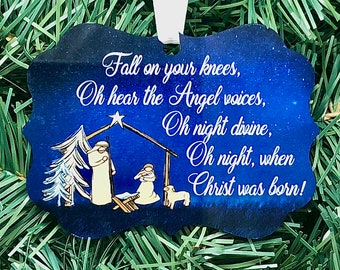 Puede incluir: Un adorno navideño azul y blanco con una escena de la natividad y el texto "Caed de rodillas, Oh escuchad las voces de los ángeles, Oh noche divina, Oh noche, cuando Cristo nació!"