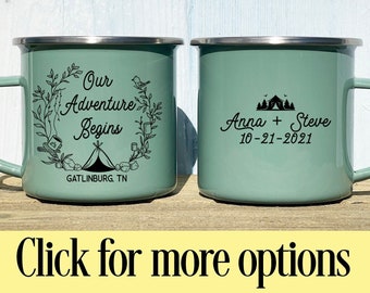 May include: Two teal enamel camping mugs with silver rims. One mug features the text "Our Adventure Begins" with a floral design and "Gatlinburg, TN." The other mug has "Anna + Steve" and the date "10-21-2021."