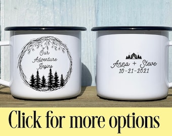 May include: Two white enamel mugs with black rims. One mug has a black and white design of a wreath with pine branches and trees with the text "Our Adventure Begins". The other mug has a black and white design of a tent with trees and the text "Anna + Steve 10-21-2021".
