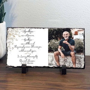 May include: A black slate plaque with a photo of a man and a memorial message. The message reads "Goodbyes are not forever. Goodbyes are not the end. They simply mean I'll miss you until we meet again. In Loving Memory Of Daniel Jenson June 13, 1957 - July 28, 2024"