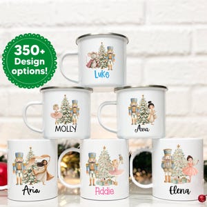 May include: White enamel mugs with various designs featuring a Christmas tree, nutcrackers, and ballet dancers. Each mug has a name printed on it. A green circle with the text "350+ Design options!" is also visible.