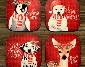 May include: Set of four square coasters featuring a penguin, polar bear, dalmatian dog, and deer wearing winter accessories. Each coaster has a red background with a white design and a festive message. The messages are "It's Christmas Time", "Warm Wishes", "Joy to the World", and "Holiday Cheers".