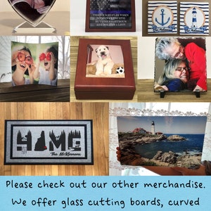 K&ouml;nnte beinhalten: Eine Sammlung personalisierter Wohnaccessoires, darunter ein herzf&ouml;rmiger Glas-Bilderrahmen, eine Holzkiste mit einem Hunde-Foto, eine Schiefer-Fotoplatte, eine Fu&szlig;matte mit dem Text "HAME" und einem personalisierten Namen sowie ein Schneidebrett aus Glas mit einem Leuchtturm-Foto.