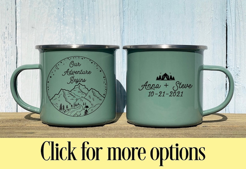 K&ouml;nnte beinhalten: Zwei gr&uuml;ne Emailletassen mit schwarzem Text und Illustrationen. Eine Tasse sagt "Our Adventure Begins" mit einer Bergszene. Die andere Tasse sagt "Anna + Steve 10-21-2021" mit einem Zelt und B&auml;umen.