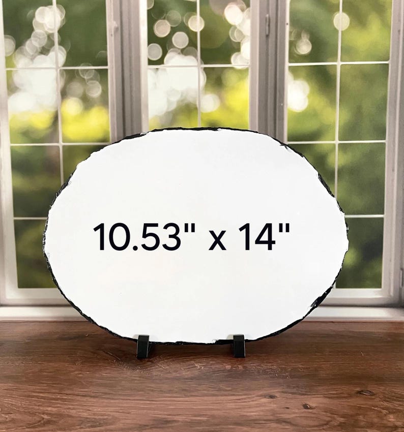 May include: An oval-shaped white slate plaque with a rough, dark, textured edge. The center of the plaque features the black printed text 10.53" x 14". The plaque is supported by two small black stands at the base, displaying its dimensions clearly.
