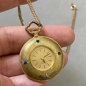 Vintage handmatig opwindbaar draaiend horloge met hanger, opgerolde gouden ketting, veelkleurige Starburst-steentjes