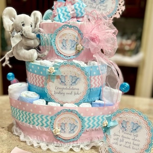 Gâteau de couches premium à 4 niveaux, rose/bleu avec agneau farci, tétines, brosse/peigne, gants de toilette, enseigne pour gâteau, carte de table et décoration de gâteau