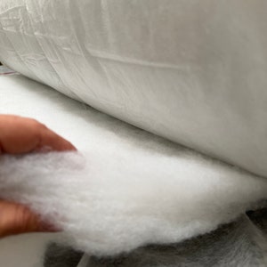 May include: A close-up of white polyester fiberfill, commonly used for stuffing pillows, cushions, and other soft goods.